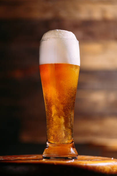 Sparkling beer in yard glass Yard of beer sparkling with foam over wood textured background pilsen stock pictures, royalty-free photos & images