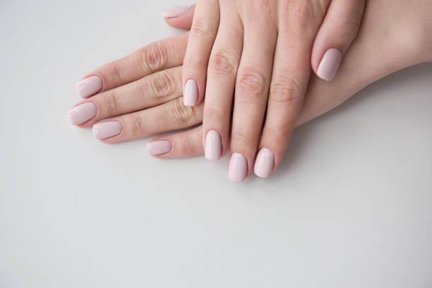 Manicured hands on white background. Hands with manicured nails colored with beige nail polish. stock photo