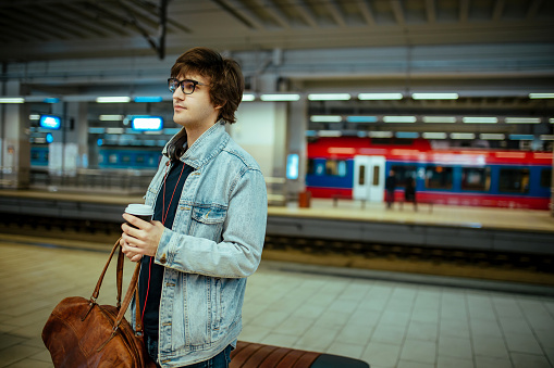 Hipster businessman drinking coffee at the train station