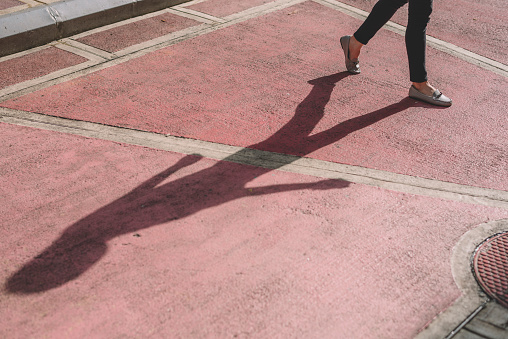 an asian chinese female's legs and her body shadow at the back alley of street in kuala lumpur