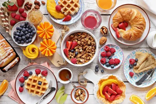 Happy breakfast with granola, croissant, fresh waffles, fruits and berries.