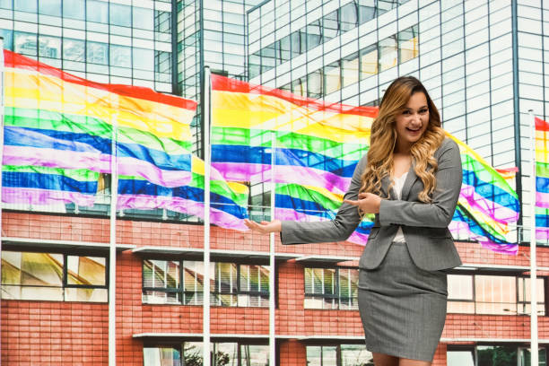 businesswoman in front of gay flag and is happy - homosexual gay pride business rainbow imagens e fotografias de stock