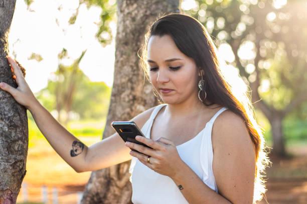 istock young girl using her mobile phone in the park 1142267317