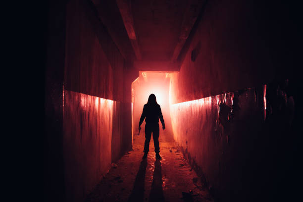 Creepy silhouette with knife in the dark red illuminated abandoned building. Horror about maniac concept Creepy silhouette with knife in the dark red illuminated abandoned building. Horror about maniac concept. serial killings photos stock pictures, royalty-free photos & images