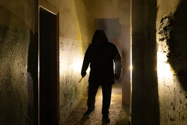 Creepy silhouette with knife  in the dark abandoned building. Horror about maniac concept.