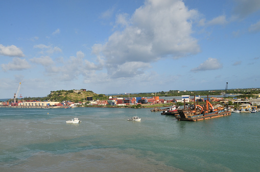 St John’s Harbor, Antigua, with barges and commercial areas and Fort James on the hill in the background