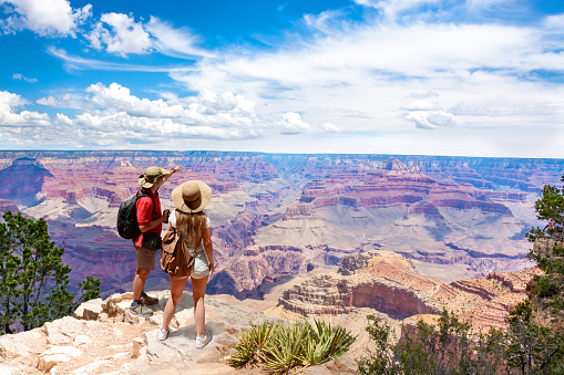Couple on top of the mountain, looking at beautiful summer mountain  landscape. Friends on hiking trip enjoying view of Colorado river. South Rim. Grand Canyon National Park, Arizona, USA.