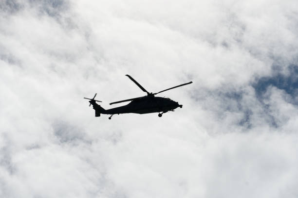 istock Silhouette army helicopter hovering on a beautiful blue cloudy sky background 1142285024