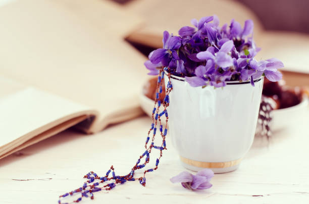 istock Still life with violet in white cup, old books. Romantic spring floral background. 1142286469