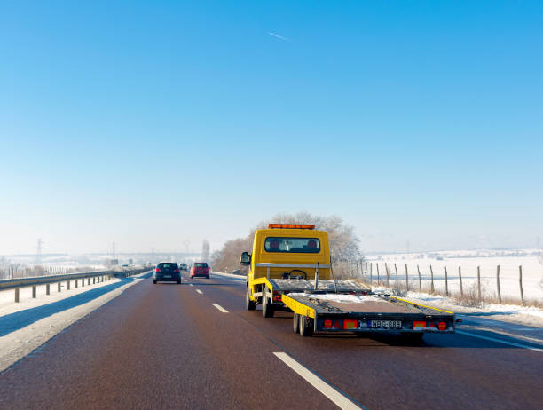 o caminhão de reboque amarelo com plataforma vazia move-se na estrada no inverno - evacuação e relocação - fotografias e filmes do acervo