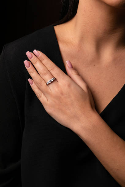 istock Womens silver diamonds ring with a fringe on finger, on a black background. 1142298049