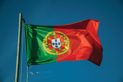 Close-up of Portuguese flag at sunset fluttering in the wind with blue sky in the background near Elvas. A gracious star-shaped fortress city on the easternmost frontier of Portugal.