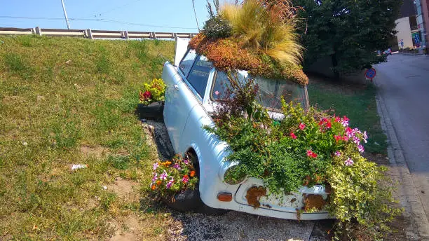 Budapest, Hungary - Aug 8, 2018: Beautiful funny vintage Trabant car parking behind an unknown parking house planted colorful flowers