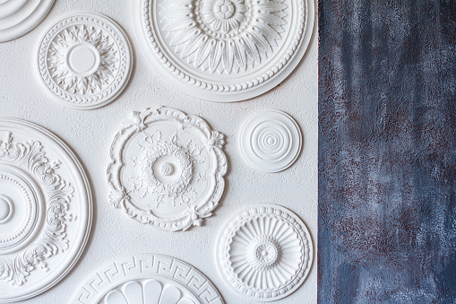 A two-color background, gray decorative plaster and a white wall with several white ceiling rosettes.