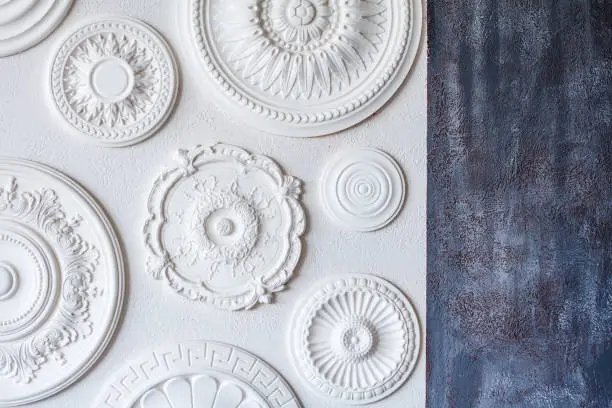 Photo of A two-color background, gray decorative plaster and a white wall with several white ceiling rosettes