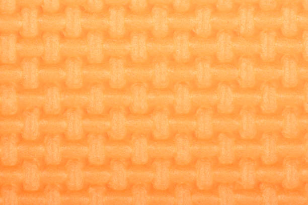 Texture of a polyethylene orange shine gym mat. Yoga mat texture. Orange polyethylene foam travel mat texture. High resolution photo.
