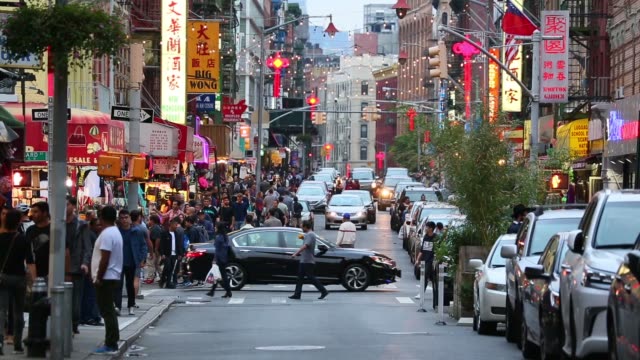 A busy city street scene with people, cars and traffic at dusk. Mott St, Chinatown, New York City. Matching day shot available. HD