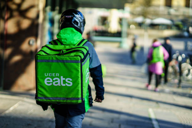Uber eats delivery person carrying food to people who order by online app Gothenburg, Sweden - April 11, 2019: Uber eats delivery person carrying food to people who order by online app motor living stock pictures, royalty-free photos & images