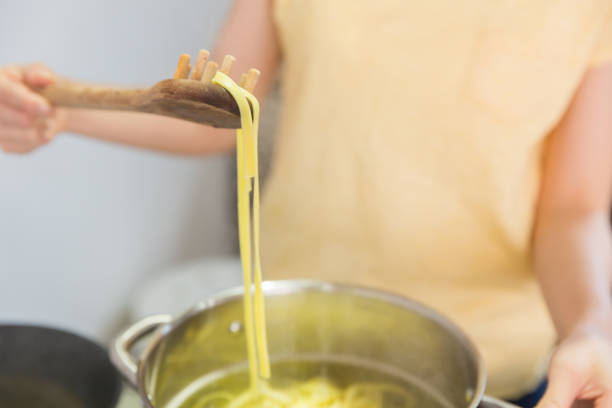 young attractive asian woman cooks in a kitchen,pasta,hands