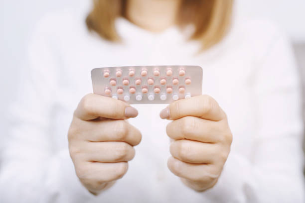 woman hands opening birth control pills in hand. eating contraceptive pill. contraception reduces childbirth and pregnancy concept. - contraceção imagens e fotografias de stock