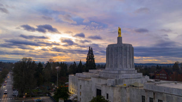 Morning Traffic Passes the Oregon Pioneer atop the Capital Building Salem The state capital building adorned with the Oregon Pioneer with downtown Salem in the background united states capitol rotunda photos stock pictures, royalty-free photos & images