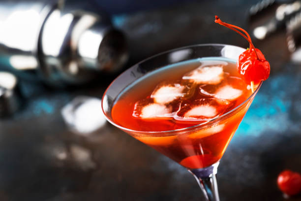istock Classic alcoholic cocktail Manhattan with bourbon, red vemuth, bitter, ice and cocktail cherry in glass, gray bar counter background, place for text, selective focus 1142351236
