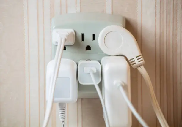 Photo of Electrical socket overloaded on wall. Electric wires plugged into socket
