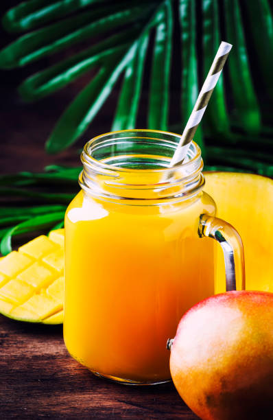 istock Fresh mango juice in large glass jar with fresh fruit on rustic wooden tropical background, copy space, selective focus 1142351377