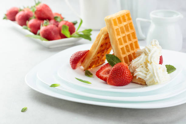 Belgian waffles with strawberries and cream garnished with fresh mint.