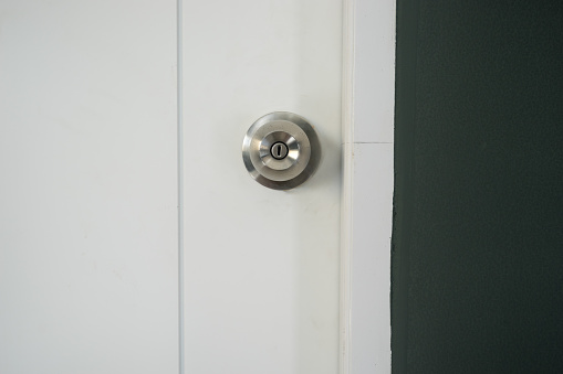 silver knob on white wood door and dark gray wall - can use to display or montage on product