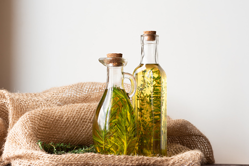 Bottles of olive oil with thyme and rosemary on a light background.