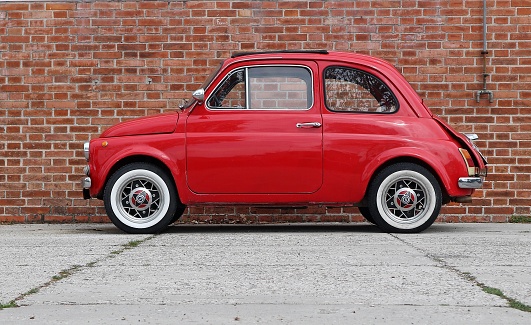 Udine, Italy. April 12 2019. An iconic vintage red Fiat 500 recently restored on brick wall background