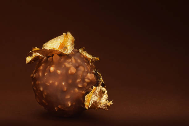 Chocolate praline with edible gold on dark brown background low key
