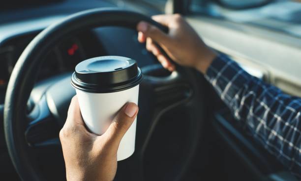 istock Man holding coffee paper cup in car 1142361170