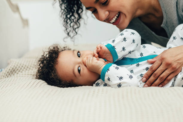 istock Happy smiling mother lying on a bed and looking on her baby son 1142361314