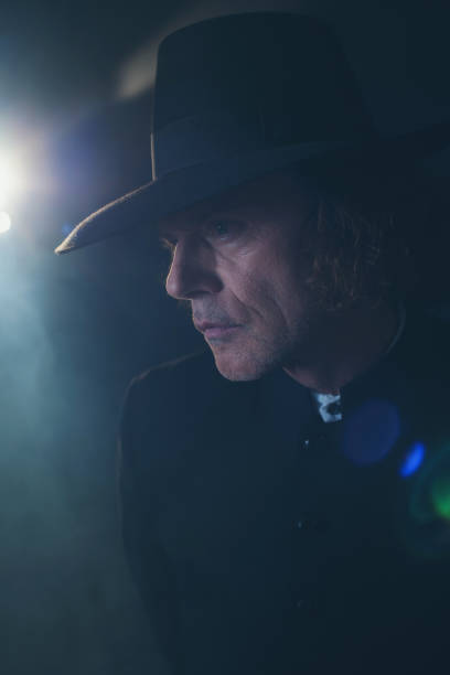 istock Mysterious victorian priest in black coat and hat in fog. 1142361865