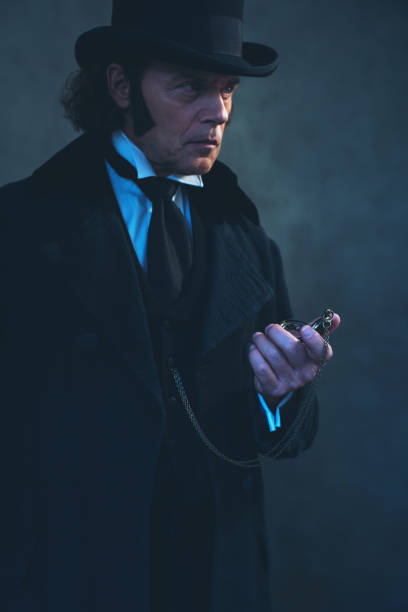 istock Edwardian man in long black coat and hat holding pocket watch. 1142361949