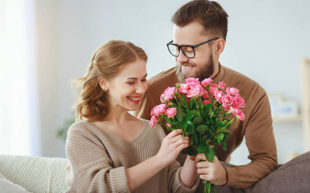 feliz casal amoroso. marido dá sua esposa flores em casa - valentines day gift rose flower - fotografias e filmes do acervo