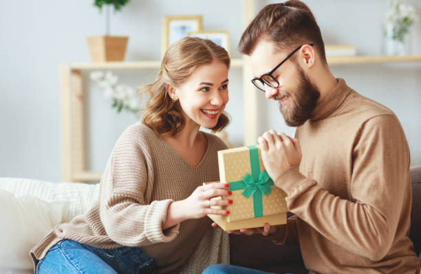 幸せな結婚カップルの男と女性は休日のための贈り物を与える - boyfriend ストックフォトと画像
