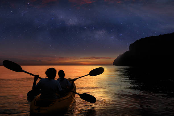 silhouette mère et descendant kayak dans l’océan avec des millions d’étoiles galaxie - kayaking kayak sea coastline photos et images de collection