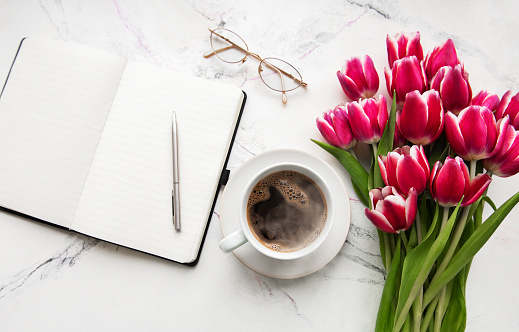 Notebook, gift box and pink tulips on a white marble background