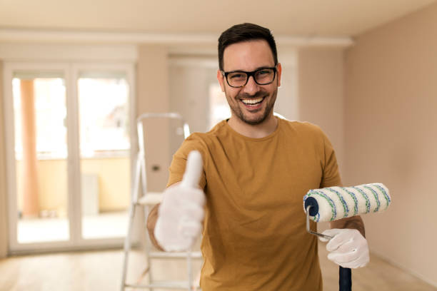 istock Young man holding painting roller and giving thumb up 1142365486