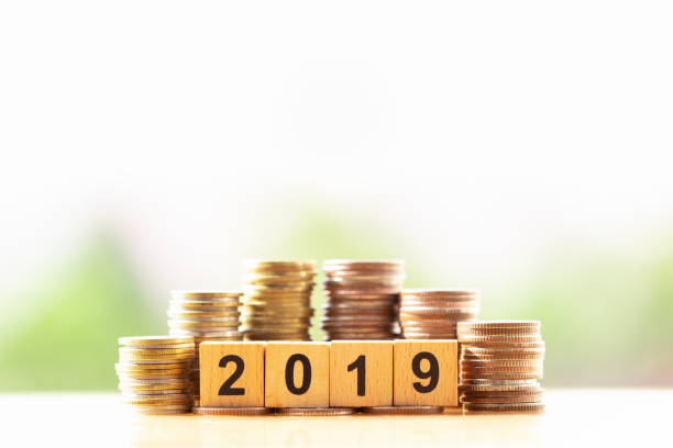 istock Wooden block number year 2019 and coins stack on greenery nature background with copy space. 1142366402