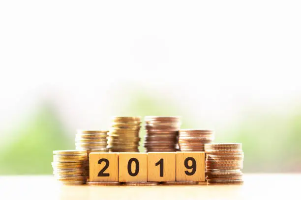 Wooden block number year 2019 and coins stack on greenery nature background with copy space. happy new year