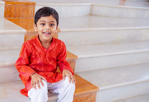 Portrait, Indian, Hindu, Celebration - An Indian Playful Kid Seated on the Temple's Marble Steps and Looking at the Camera for a Portrait