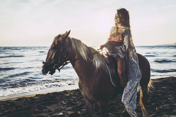 istock Young happy woman horseback riding during summer day on the beach. 1142368310