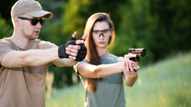 der lehrer lehrt das mädchen, eine pistole auf der reichweite zu schießen - gun women handgun armed forces stock-fotos und bilder