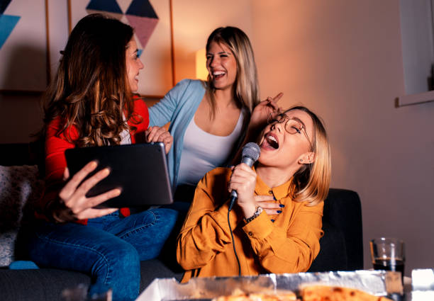 istock Three female friends having fun playing karaoke at home. 1142384854