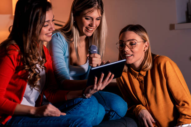 istock Three female friends having fun playing karaoke at home. 1142385019