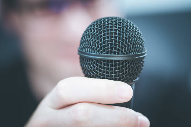 istock Speaking in the microphone: Young man with blurry face is taking into the microphone 1142396686